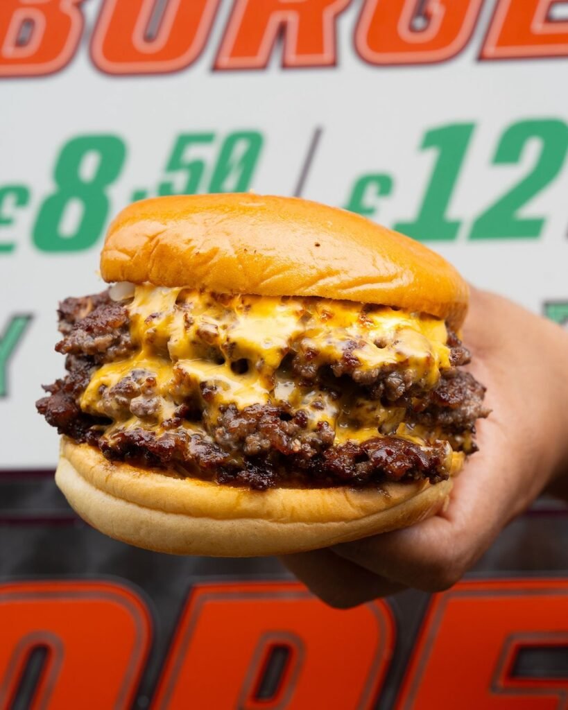 A juicy beef burger loaded with melted cheese, topped with lettuce and tomato, inside a lightly toasted bun.