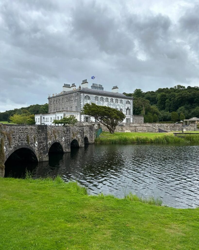 Westport House, a historic Georgian estate in County Mayo, Ireland, surrounded by lush greenery, a stone bridge, and tranquil waters