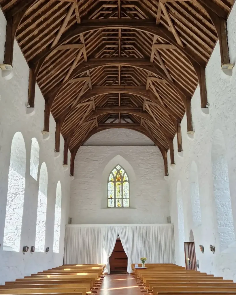 The interior of Ballintubber Abbey, County Mayo, featuring a traditional Irish oak roof constructed without nails, whitewashed stone walls, arched windows