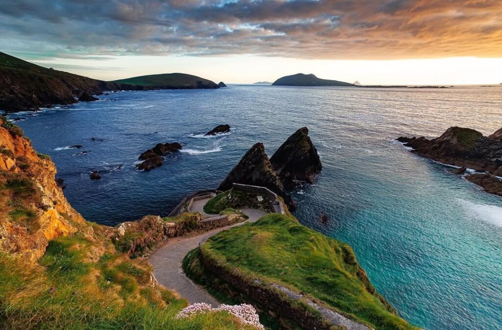 Slea Head Drive on the Dingle Peninsula in Ireland, showcasing rugged cliffs, turquoise waters, and dramatic coastal views under a vibrant sunset sky