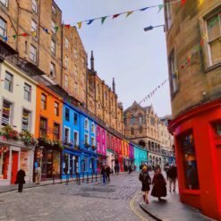 Edinburgh's Victoria Street with colorful shopfronts, historic architecture, and vibrant bunting, a popular Instagram spot.