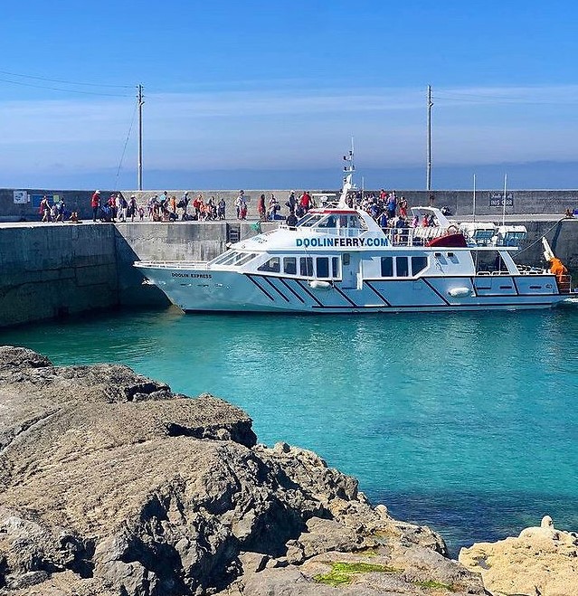 The Doolin Ferry boat docked at the harbor, with passengers boarding.