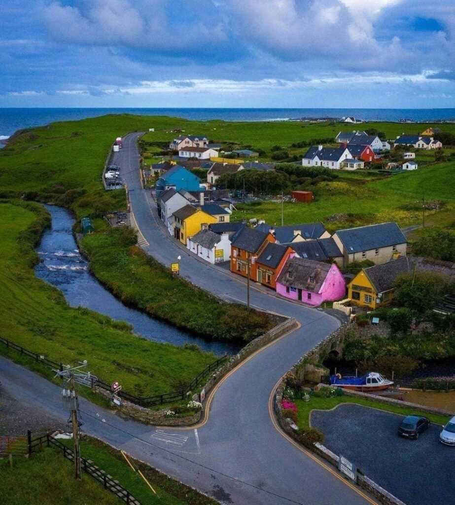A vibrant view of Doolin Village, with colorful cottages lining the road and the beautiful coastal scenery in the distance.