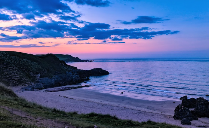 Peaceful beach Sango Sand Oasis at sunset along the  with gentle waves and a glowing horizon.