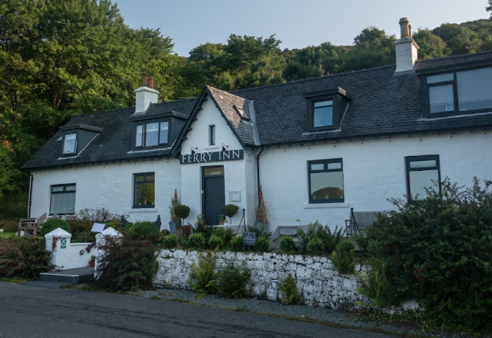 The Ferry Inn, a charming white building surrounded by greenery.