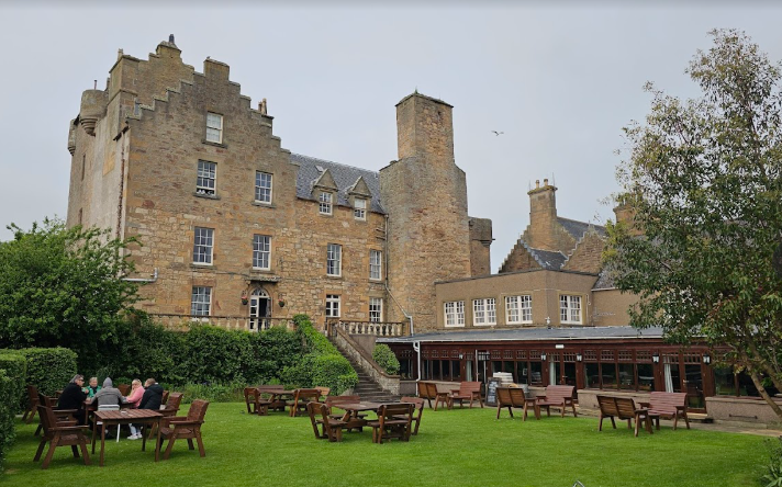 Dornoch Castle Hotel, a historic stone building with outdoor seating on the lawn.