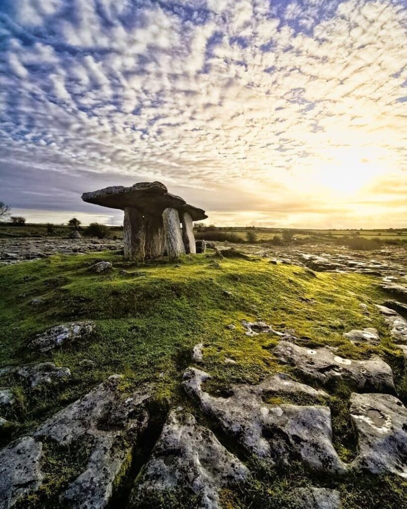 The Poulnabrone Dolmen, a prehistoric stone tomb in the Burren, Ireland, surrounded by limestone rock and a beautiful sky.