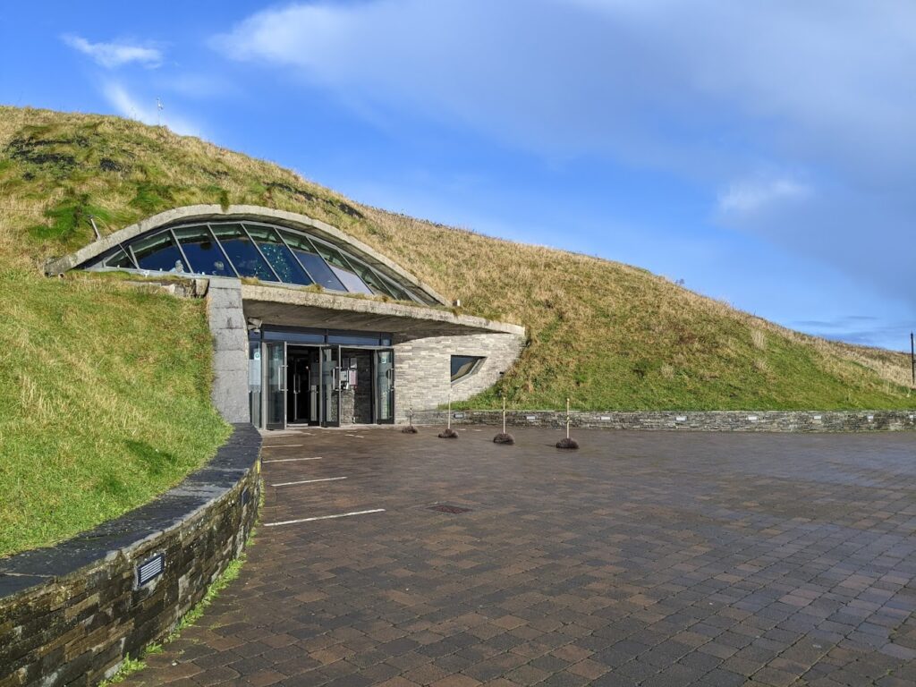 The Cliffs of Moher Visitor Center, featuring a unique, modern design with a grass-covered roof blending into the natural surroundings.
