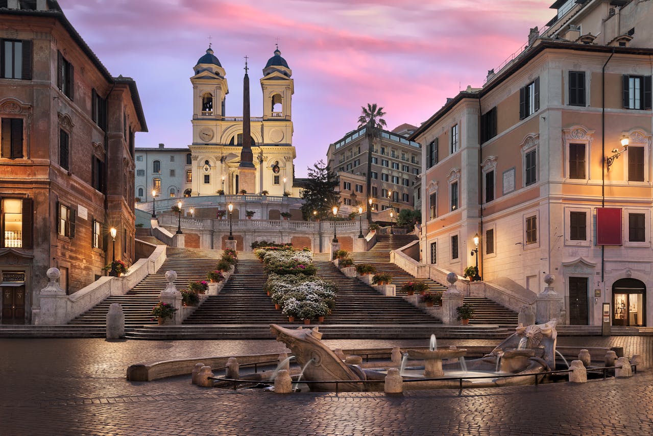 Spanish Steps in Rome at sunset, with Trinità dei Monti church and Fontana della Barcaccia in view.