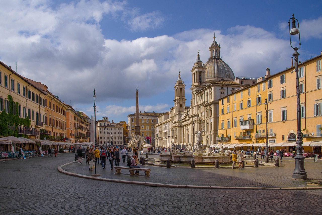 Piazza Navona in Rome, featuring Sant'Agnese in Agone, the Fountain of the Four Rivers, and a lively crowd.